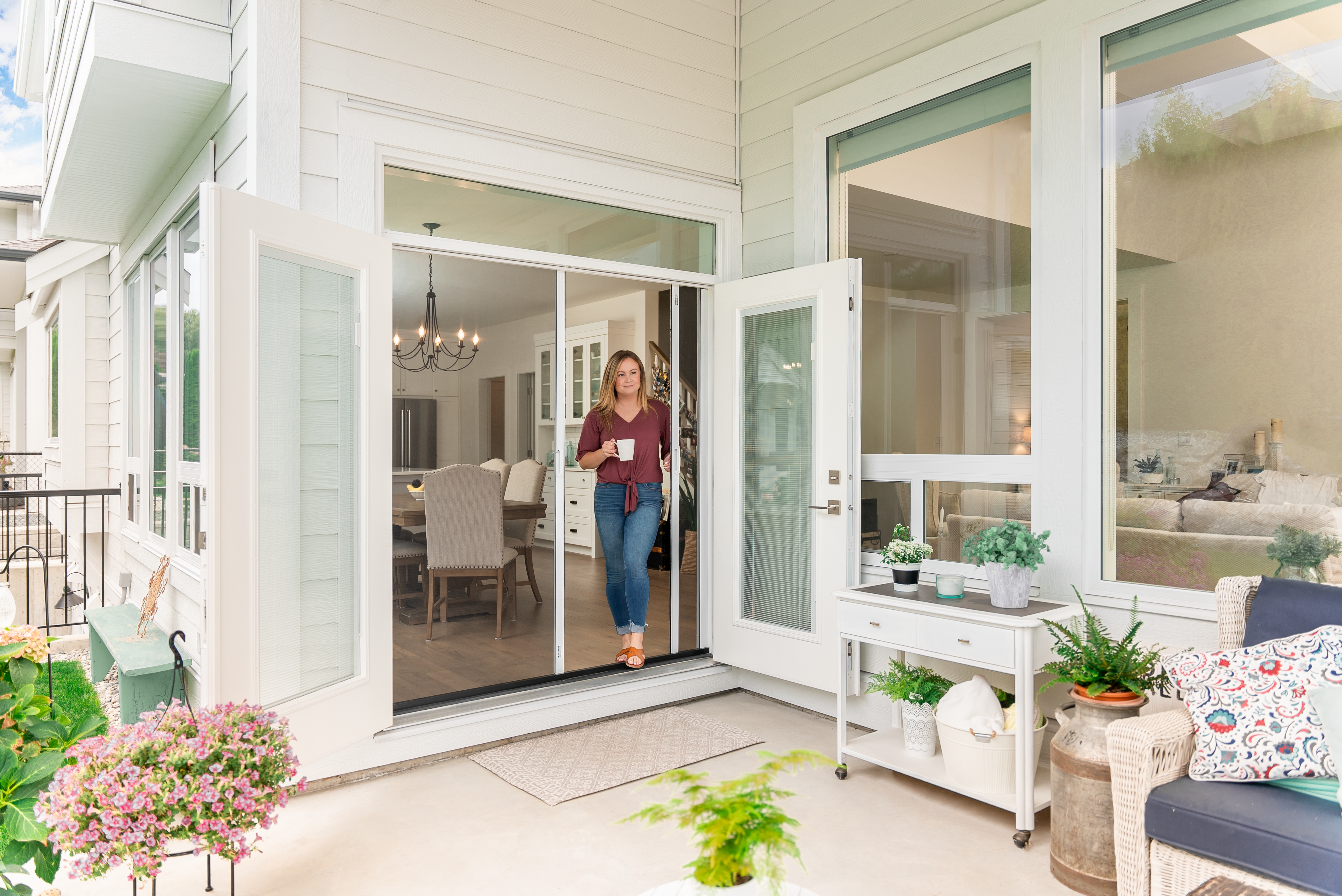 A beautiful woman with a mug on hand getting to the outside from a double french door that is covered with Phantom retractable screens